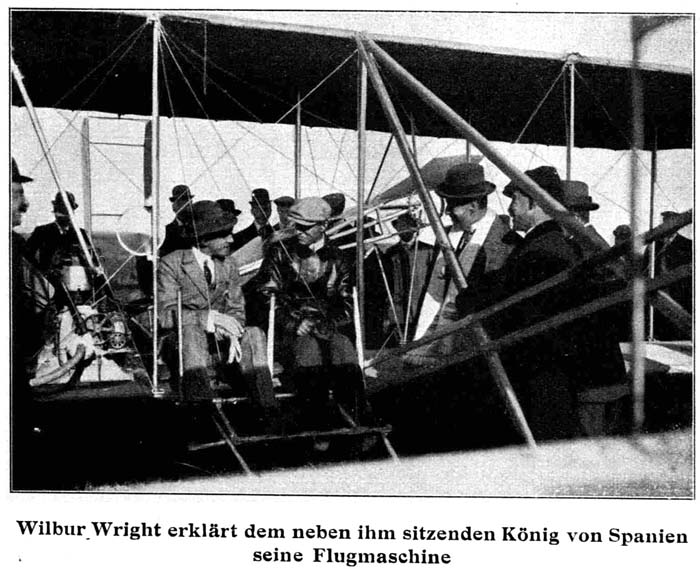 Wilbur Wright erkl&auml;rt dem neben ihm sitzenden K&ouml;nig von Spanien seine Flugmaschine.