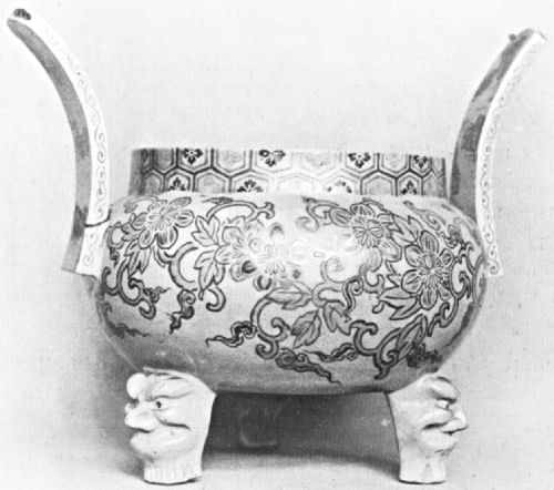 A floral motif dish with two handles and three feet, the latter in the shape of faces