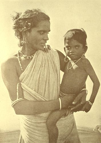 A village woman of the Shanar Caste. The photo shows the baby's ears being prepared for the jewels her mother hopes will fill them by and by. Holes are made first and filled with cotton wool, graduated leaden weights are added till the lobes are long enough.