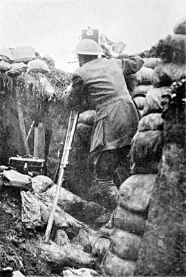FILMING THE PRELIMINARY BOMBARDMENT OF THE BIG PUSH, JULY 1ST,
1916. A FEW MINUTES AFTER THIS PHOTOGRAPH WAS TAKEN A SHELL
BURST WITHIN SIX YARDS, SMASHING DOWN THE TRENCH WALLS AND
HALF BURYING ME. NOTE THE SANDBAG ON A WIRE IN FRONT OF MY
CAMERA FOR "CAMOUFLAGE"