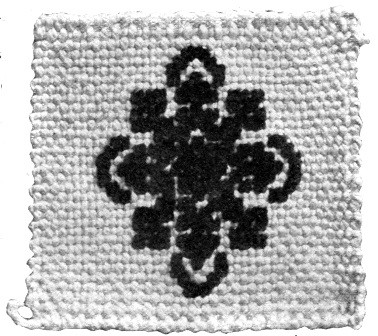 A square of silk canvas with cross-stitched pattern of
chenille