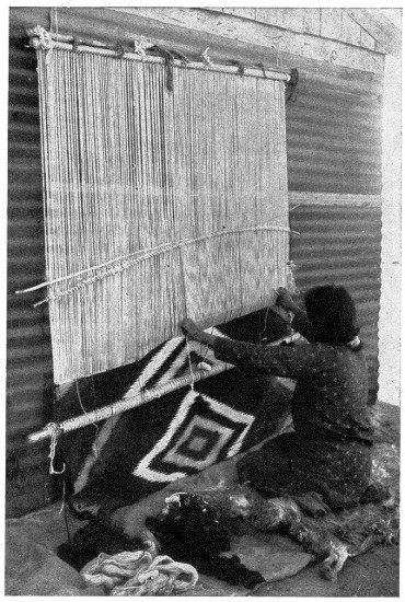A Navajo Indian woman weaving a blanket