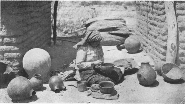 In the bright Arizona sunshine before their little square
adobe houses Indian women are fashioning pottery into curious shapes