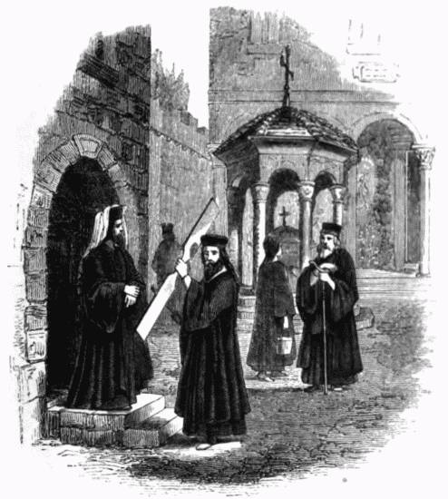 From a Sketch by R. Curzon.
Interior of the Court of a Greek Monastery. A monk is calling the congregation to
prayer, by beating a board called the simandro (σιμανδρο) which is generally used instead
of bells.