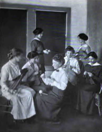 A Knitting Class at the Agricultural School. Note the
splendid poise of the Country Girl in the background, how naturally and
yet perfectly she is holding herself.