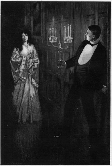 A man, dressed in evening clothes and holding a candleabra, looks at a woman dressed in a long gown.