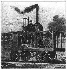 A photograph of a very small locomotive, with a man standing on its platform.