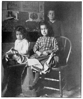 A photograph of two little girls with sewing in their laps.