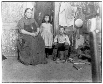 A woman and a boy are seated, and a girl stands.