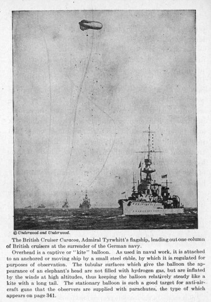 The British Cruiser Curacoa, Admiral Tyrwhitt's flagship, leading out one column of British cruisers at the surrender of the German navy.  Overhead is a captive or "kite" balloon.  As used in naval work, it is attached to an anchored or moving ship by a small steel cable, by which it is regulated for purposes of observation.  The tubular surfaces which give the balloon the appearance of an elephant's head are not filled with hydrogen gas, but are inflated by the winds at high altitudes, thus keeping the balloon relatively steady like a kite with a long tail.  The stationary balloon is such a good target for anti-aircraft guns that the observers are supplied with parachutes, the type of which appears on page 341.