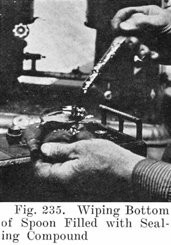 Fig. 235 Wiping bottom of spoon filled with sealing compound