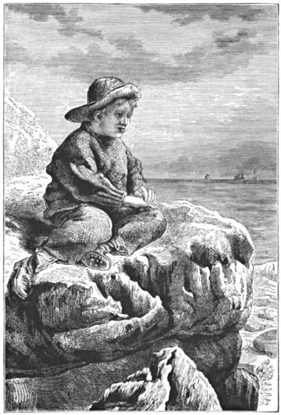 A boy sits on a rock, looking out to sea