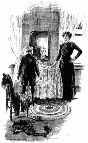 Killis in fancy old-fashioned clothes looking into a small mirror hanging above a table. Miss Loring is standing by the side of the table with a serious expression, one hand on her hip and the other touching the table. In the foreground, clothes lie about on the floor and on the chair.
