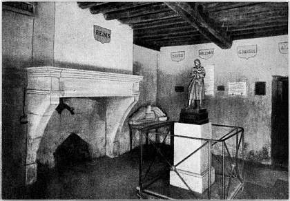 Kamer in het huis waar Jeanne d'Arc te Domremy woonde.
   Het huis wordt zooveel mogelijk in den oorspronkelijken toestand bewaard. In het midden een standbeeld van Jeanne.--Naar een photographie.