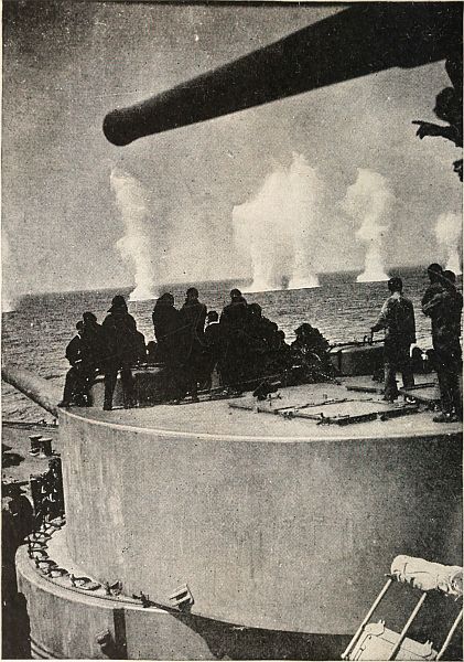 men standing on ship watching explosions off in the water