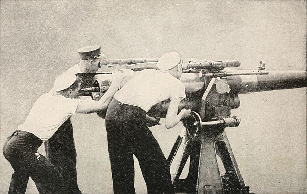 three sailors aiming a deck gun