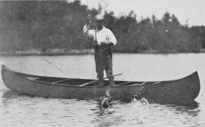 Man standing in a boot fishing. In front of him the black bass.