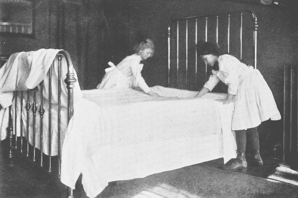 Two girls making a bed