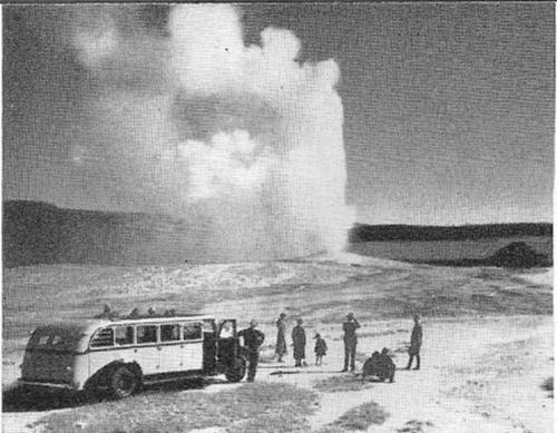 A bus load of visitors has stopped for a look at Old Faithful shooting its mighty column skyward.