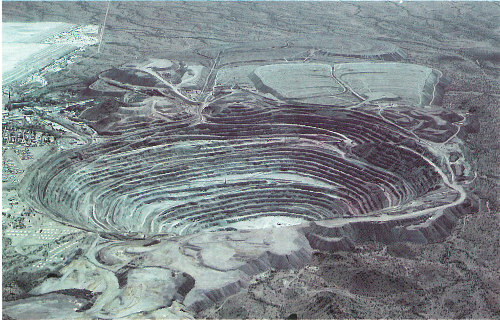 This open-pit mine in the Sonoran Desert near Ajo, Arizona, has exposed an elliptical copper deposit about 1,000 meters long and 750 meters wide. The copper ore mined here is in a bed that averages 150 meters in thickness (photograph by Peter Kresan).