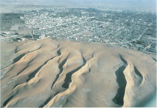 Linear dunes of the Sahara Desert encroach on Nouakchott, the capital of Mauritania. The dunes border a mosque at left (photograph by Georg Gerster).