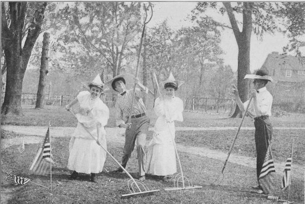 Photo of two young women and two young men with garden tools an funny sunhats