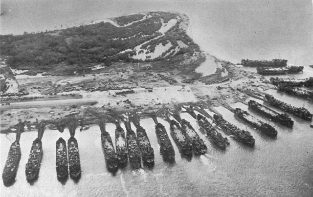 LST’S UNLOADING AT TACLOBAN AIRFIELD. The causeways leading from the beach to the ships were built by bulldozers scraping sand and earth to each ship as it landed.