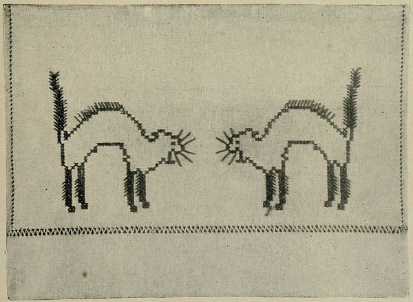 photo: two embroidered cats hissing at each other