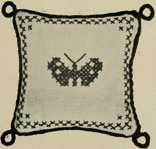 photo of square pincushion with butterfly in the center, checkerboard trim and loops at the corners