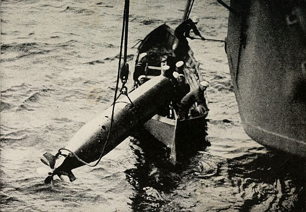 men loading torpedo into lifeboat for recovery