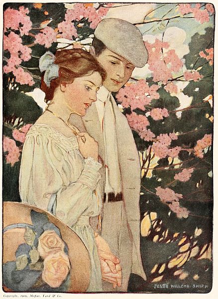young couple walking holding hands with flowers in background