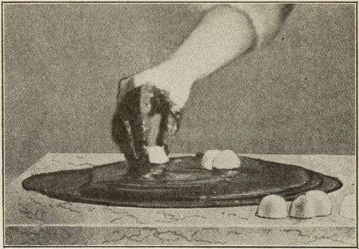 Dipping bon-bons into chocolate with chocolate covered hand