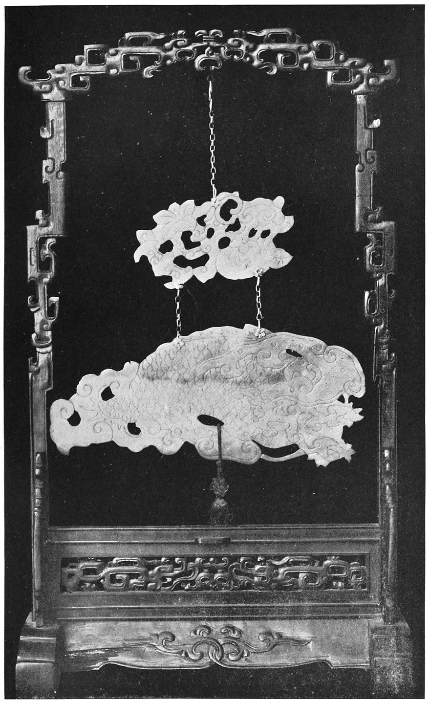 RESONANT STONE OF JADE SHOWING DRAGON WITH CLOUD ORNAMENTS, SUSPENDED FROM CARVED BLACKWOOD FRAME