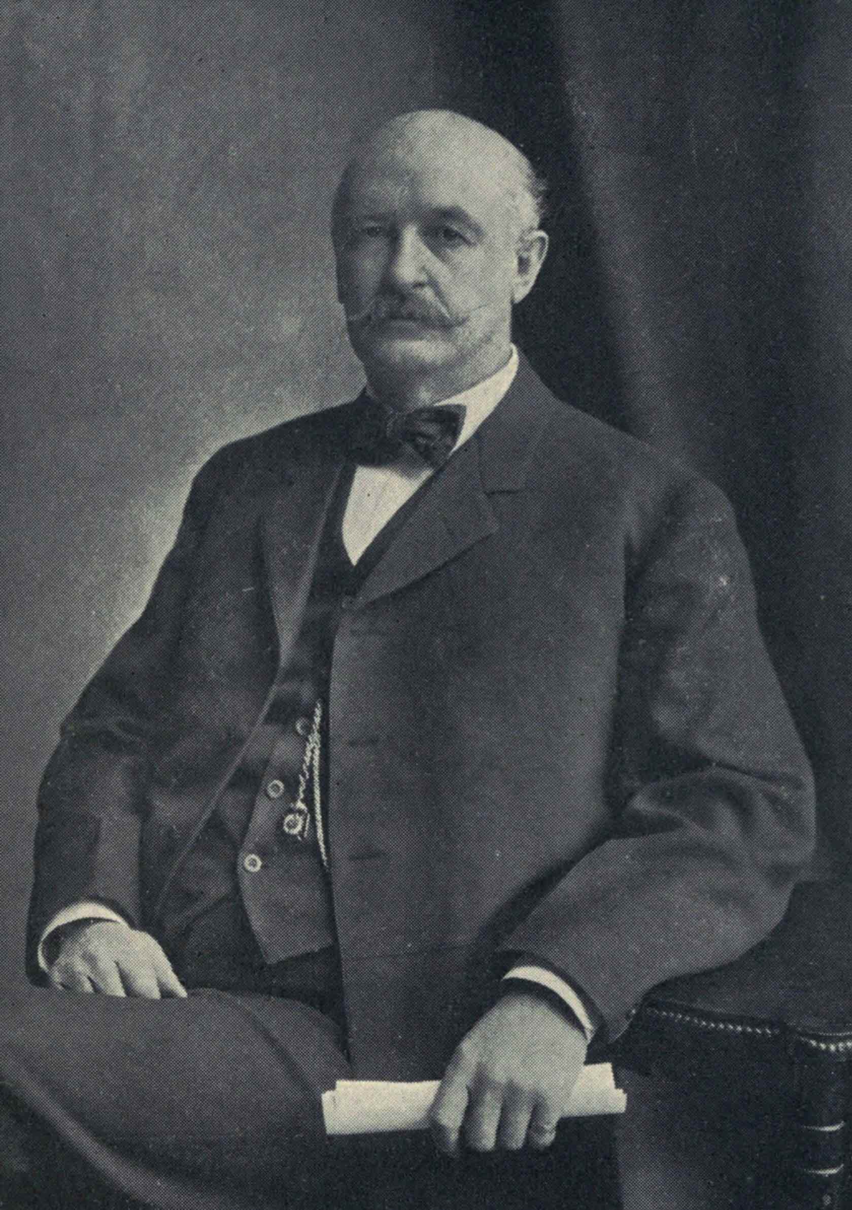 A formal portrait of David Patterson Hatch, seated in a suit with bow tie, holding a rolled paper.