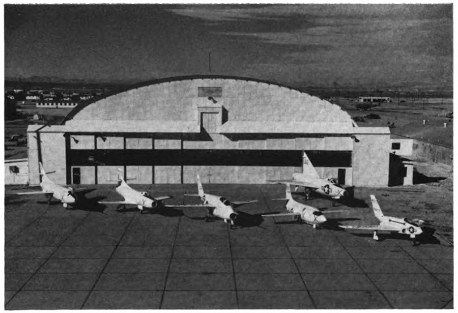 A hangar with several airplanes in front of it