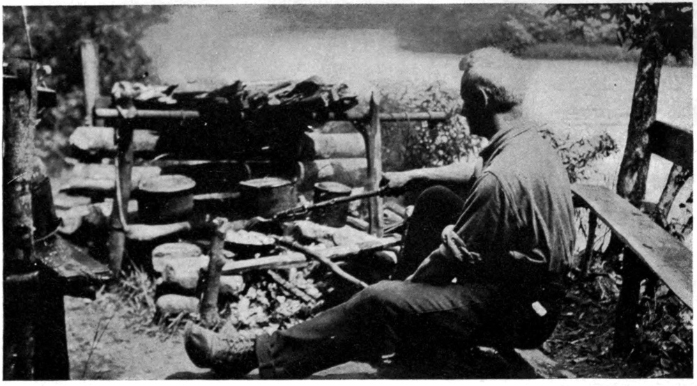 Photo of a seated man cooking outdoors.