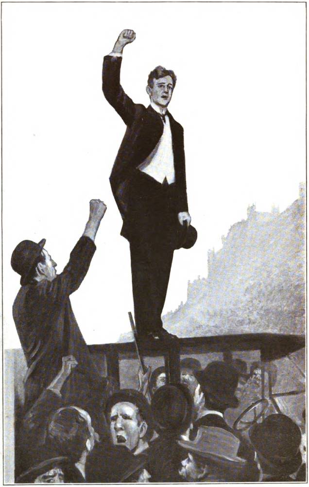 A smartly dressed man stands on the roof of a car with his right hand in the air and a hat in his other hand. A crowd surrounds the car and appears to be cheering.