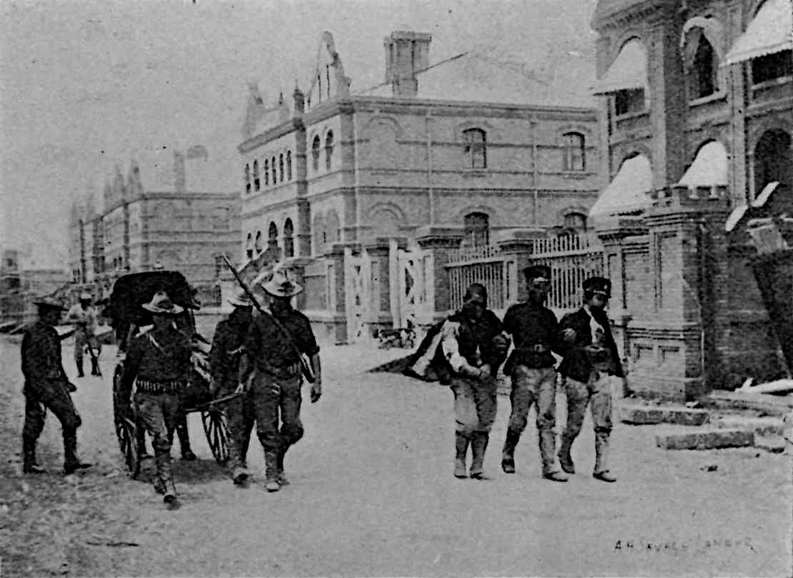 Some men walking, some wounded, with buildings behind and right, like the previous illustration