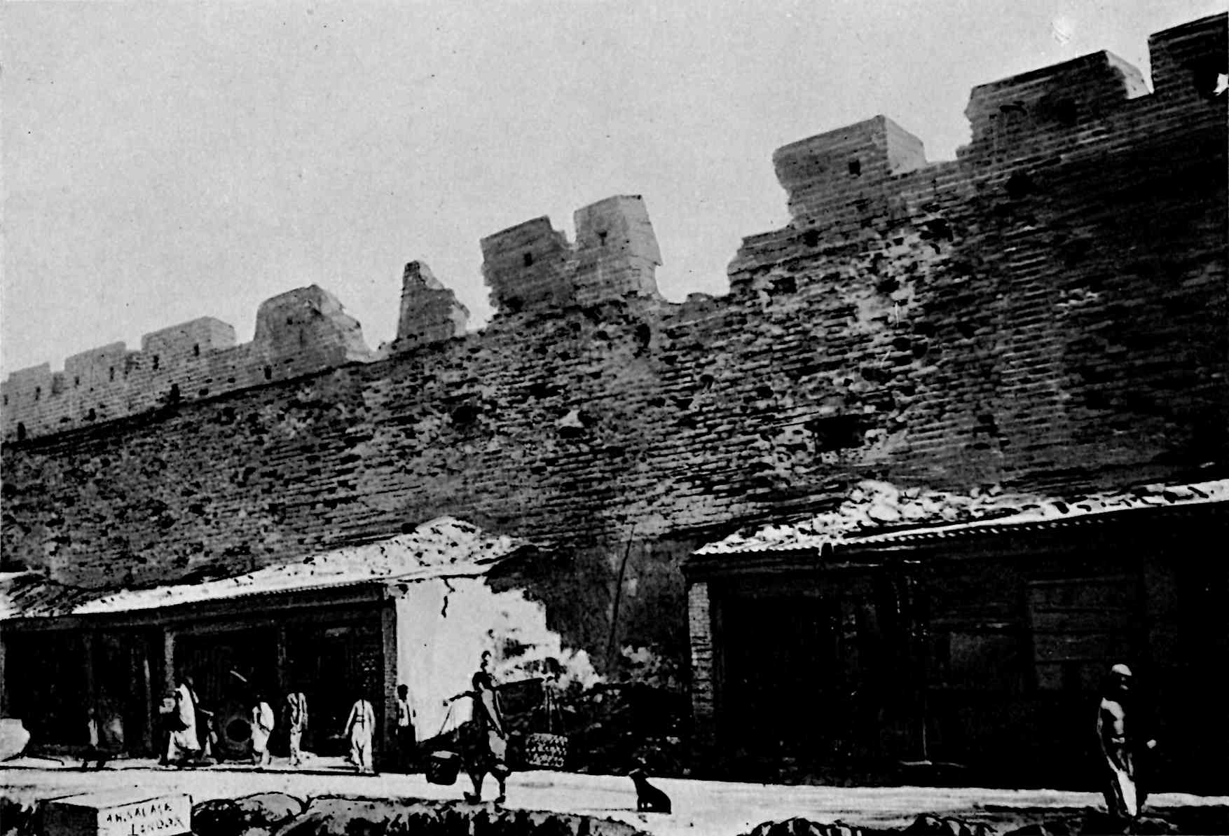 Buildings in front of wall, with sections of the top part of the wall missing