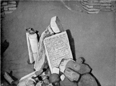 Arabic Inscription and marble columns with earthenware lamps upon them. Fragment of water-pipe. Stone implements. Brick wall of the Tombs of Forty Saints showing in top corners of photograph.