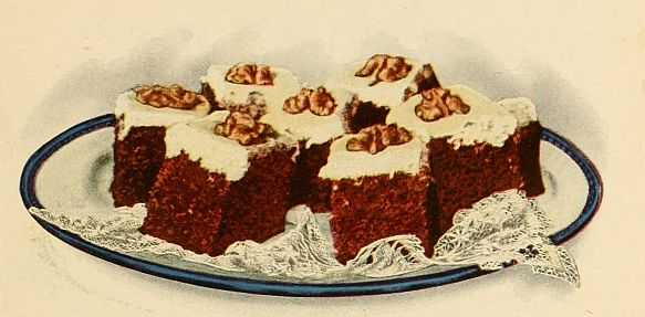 Little squares of cake with white icing and a walnut half on top