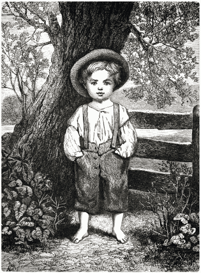 A young boy standing in front of a large tree.