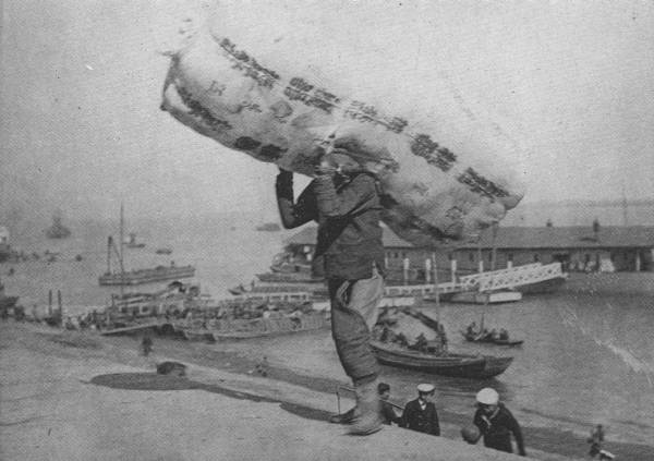 EARNING HIS LIVING

This coolie, who carries 420-lb. bale of cotton, as seen in the picture,
from the ship in the river to the Hankow Bund, probably earns a dollar
and a half per week!