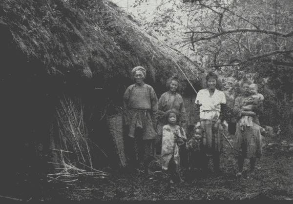 HAPPY FAMILY IN BACKWOODS

The Author spent two nights in this crudely-thatched home in the hills.
Though poor, the people were extremely hospitable—and invariably happy.