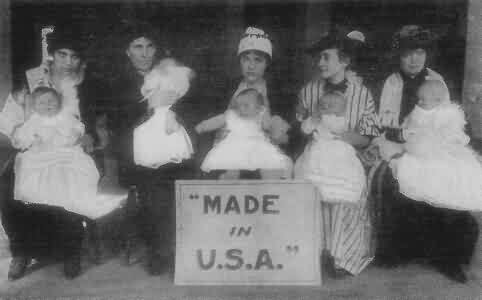 Row of Women Holding Infants in Front of Made in USA Sign