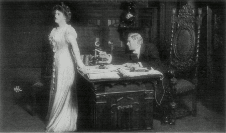 [Photo, from the play,
of Mr. Ryder discussing his son with Miss Green.]
