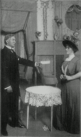 [Photo, from the play,
of Mr. Ryder holding out a cheque to Shirley.]