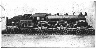 A photograph of two trains; one pulls cars that look like horse-drawn carriages, and is half the height as the 'modern' locomotive.