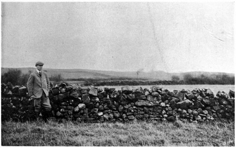 Man standing next to stone wall.