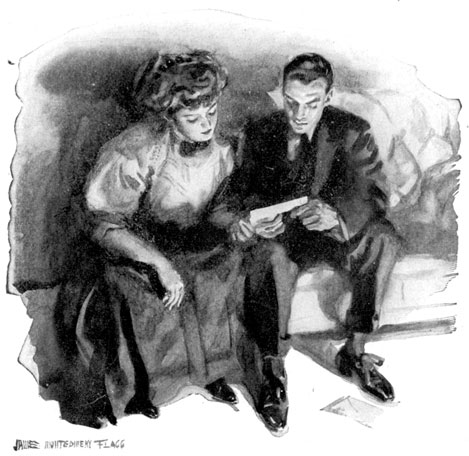A man and woman sit on a sofa and read a letter.